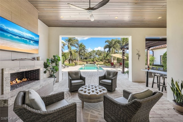 view of patio / terrace featuring an outdoor bar, ceiling fan, and a tiled fireplace