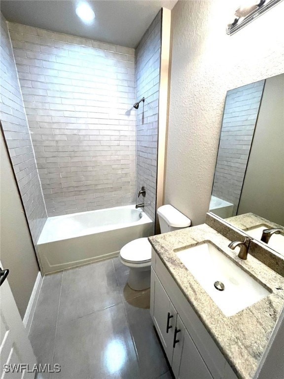 full bathroom with tile patterned flooring, vanity, tiled shower / bath combo, and toilet