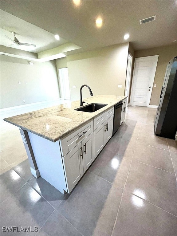 kitchen with dishwasher, white cabinets, sink, light stone countertops, and an island with sink