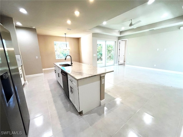 kitchen featuring appliances with stainless steel finishes, light stone counters, pendant lighting, a center island with sink, and white cabinets