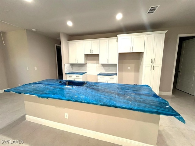 kitchen featuring backsplash, dark stone countertops, white cabinetry, and light tile patterned flooring