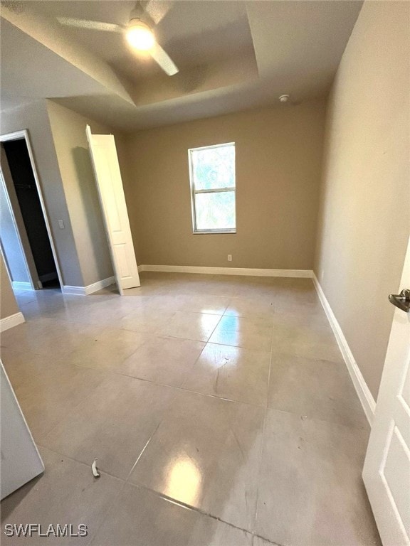 spare room featuring a raised ceiling and ceiling fan