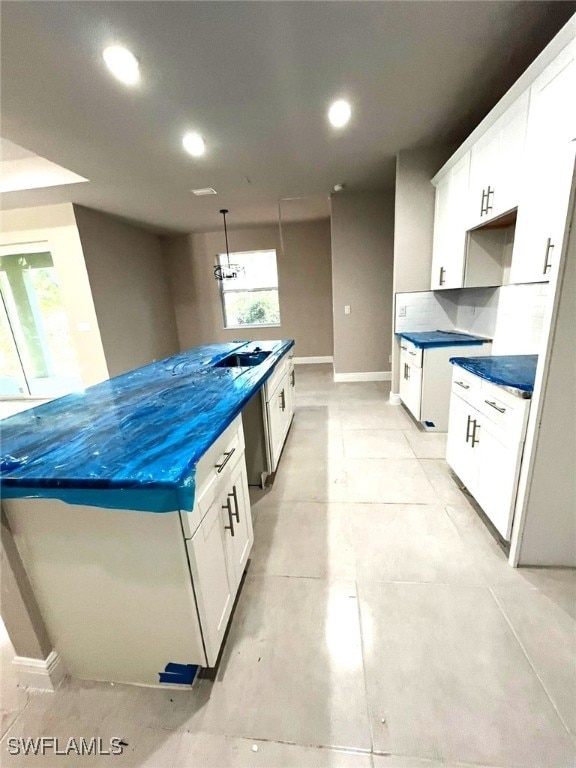 kitchen featuring a center island, white cabinets, sink, hanging light fixtures, and decorative backsplash