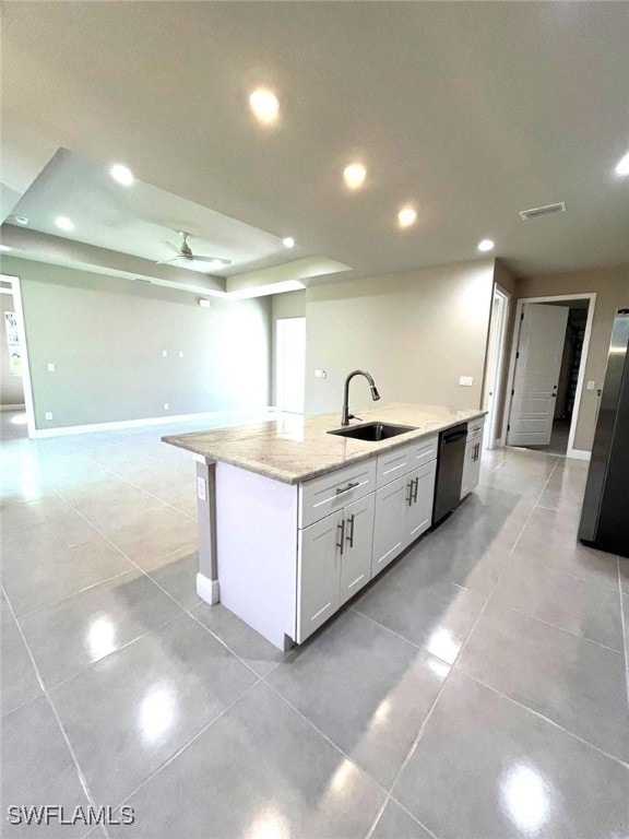 kitchen featuring dishwasher, sink, an island with sink, light stone counters, and white cabinetry