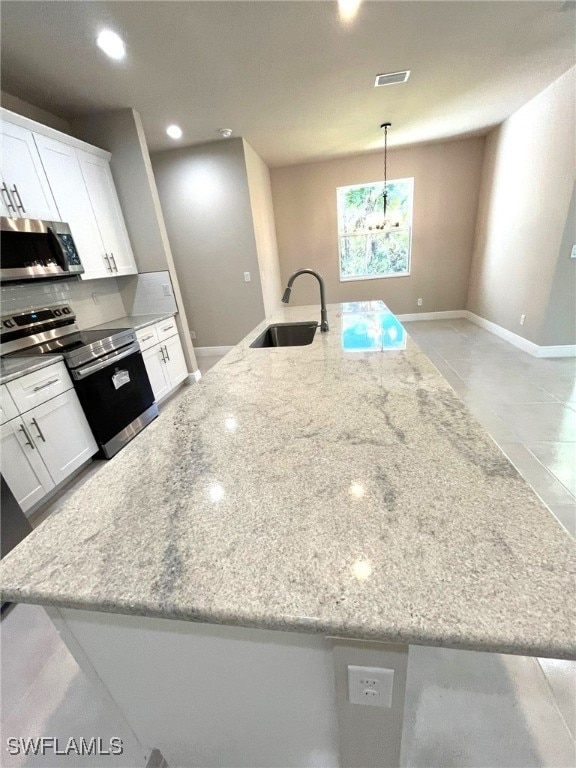 kitchen featuring pendant lighting, white cabinets, sink, light stone counters, and stainless steel appliances