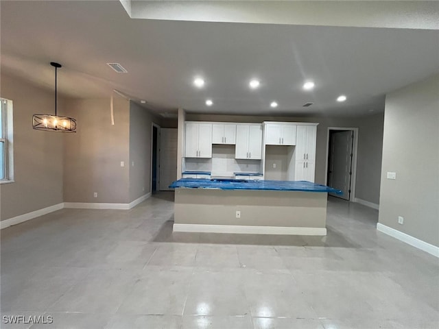 kitchen with decorative backsplash, white cabinets, a chandelier, a kitchen island, and hanging light fixtures