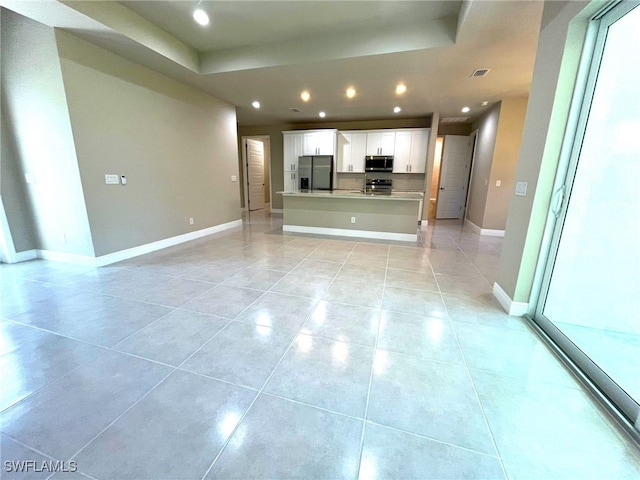 unfurnished living room with a tray ceiling and light tile patterned floors