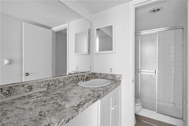 bathroom featuring tile patterned floors, toilet, vanity, and walk in shower