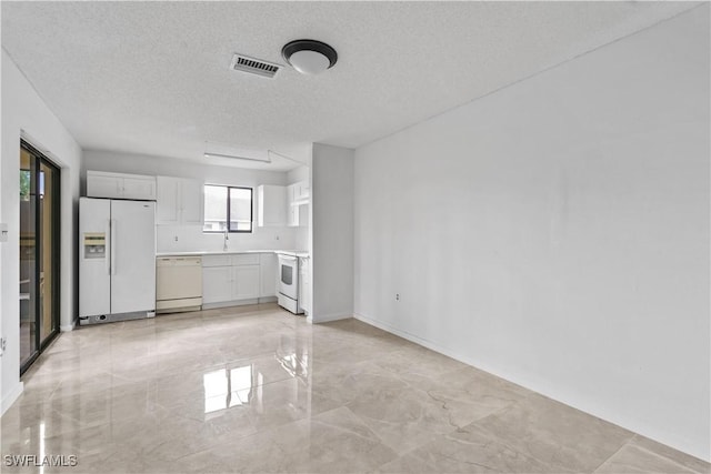 kitchen with white cabinets, a textured ceiling, white appliances, and sink