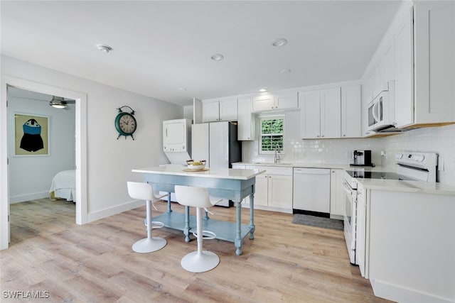 kitchen featuring white cabinetry, sink, white appliances, and light wood-type flooring