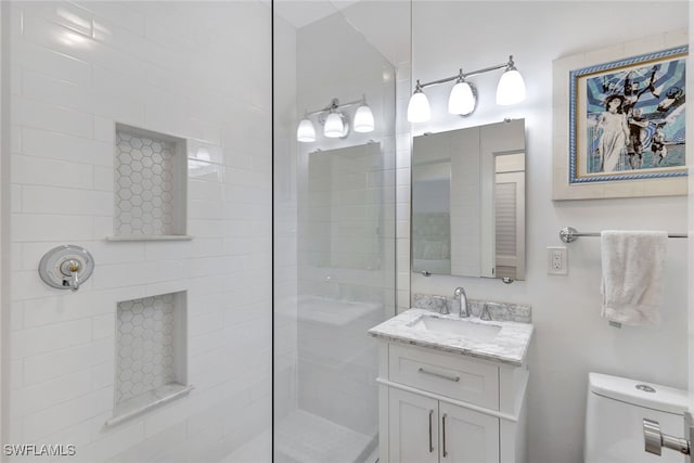 bathroom with a tile shower, vanity, and toilet