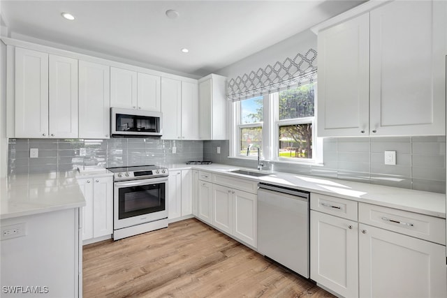 kitchen featuring white cabinets, stainless steel appliances, light hardwood / wood-style flooring, and sink