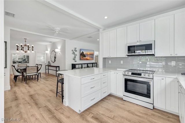 kitchen with electric range, white cabinetry, and kitchen peninsula