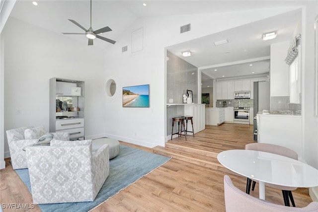 living room featuring high vaulted ceiling, light hardwood / wood-style flooring, and ceiling fan