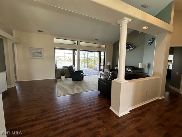 living room featuring ornate columns and dark wood-type flooring