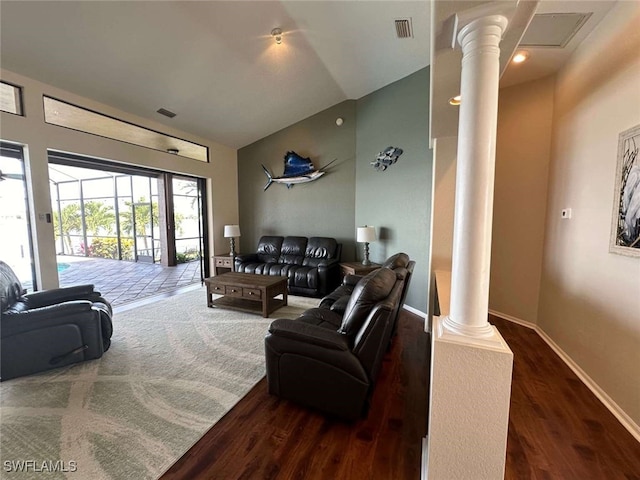 living room featuring ornate columns, dark wood-type flooring, and vaulted ceiling