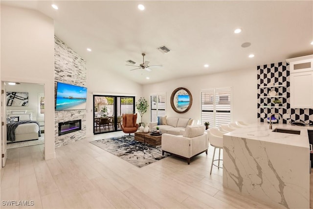 living room with ceiling fan, sink, light wood-type flooring, and a fireplace