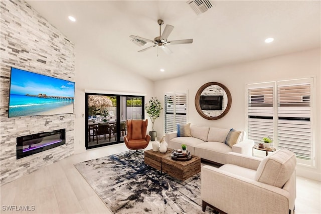 living room with a fireplace, light hardwood / wood-style floors, ceiling fan, and lofted ceiling