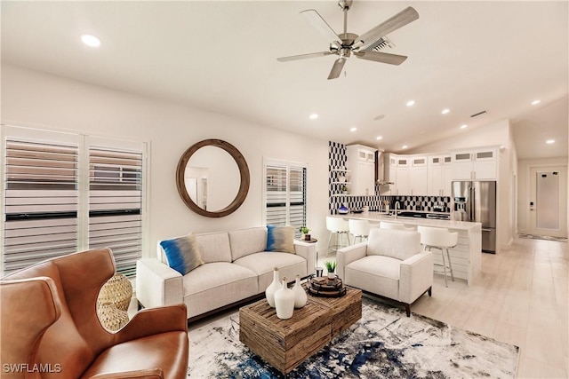 living room with light hardwood / wood-style floors, ceiling fan, and lofted ceiling