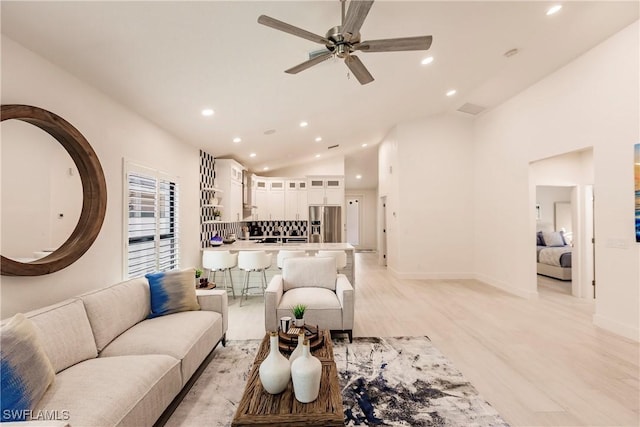 living room featuring ceiling fan, light hardwood / wood-style flooring, and vaulted ceiling