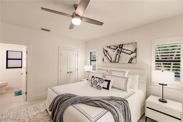 bedroom featuring ceiling fan, a closet, ensuite bath, and light hardwood / wood-style flooring