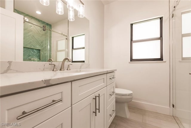 bathroom featuring vanity, toilet, and a shower with shower door