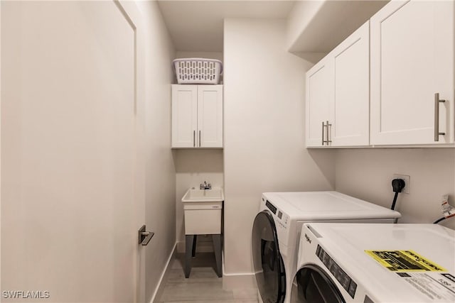 laundry area featuring washing machine and clothes dryer, light tile patterned flooring, and cabinets