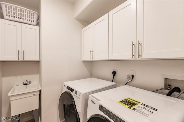 clothes washing area featuring washing machine and dryer, sink, and cabinets