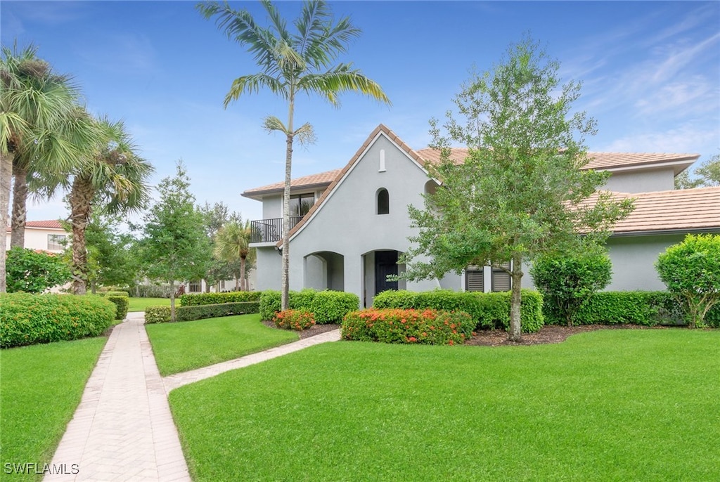 mediterranean / spanish house featuring a balcony and a front lawn