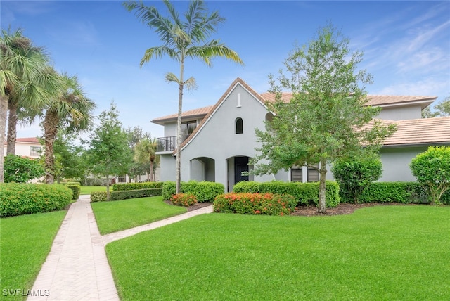 mediterranean / spanish house featuring a balcony and a front lawn