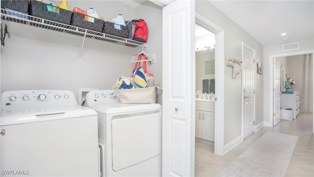 clothes washing area with light tile patterned floors and washer and dryer