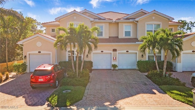 mediterranean / spanish-style home featuring a tiled roof, decorative driveway, and stucco siding