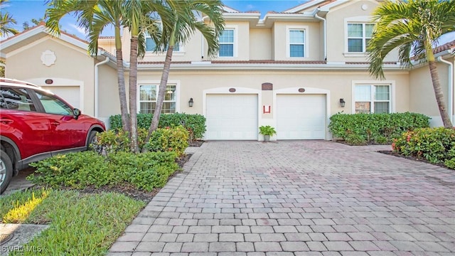 view of property with a garage, decorative driveway, and stucco siding