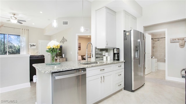 kitchen with light stone counters, stainless steel appliances, visible vents, a sink, and a peninsula