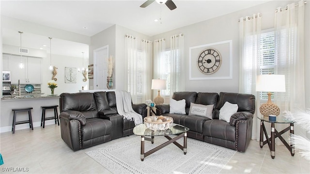 living room with a wealth of natural light, light tile patterned floors, and ceiling fan with notable chandelier