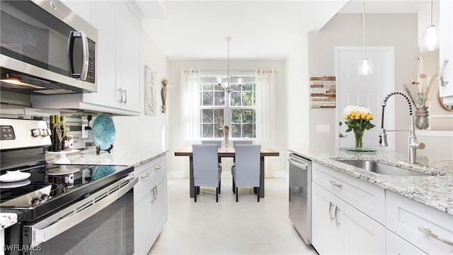 kitchen with appliances with stainless steel finishes, white cabinetry, a sink, and decorative light fixtures