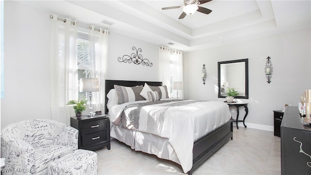 bedroom featuring ceiling fan, light tile patterned floors, and a tray ceiling