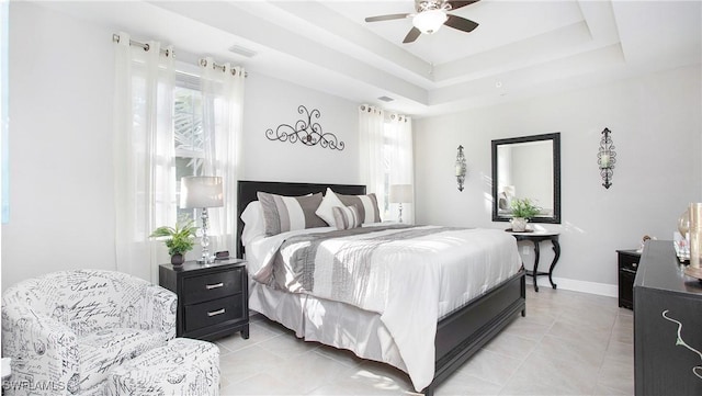 bedroom with visible vents, multiple windows, baseboards, and a raised ceiling