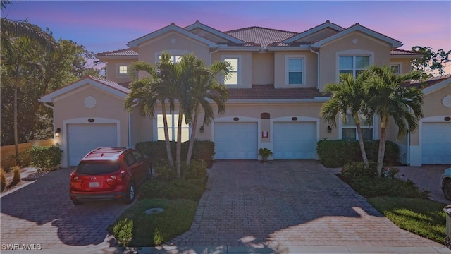 view of front of home with a tiled roof, decorative driveway, and stucco siding