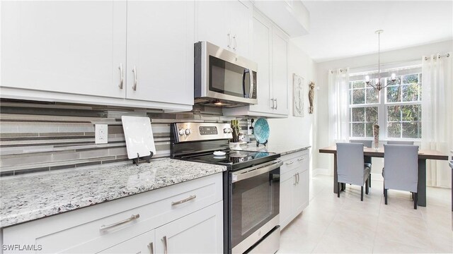 kitchen with light stone counters, light tile patterned floors, stainless steel appliances, backsplash, and white cabinetry