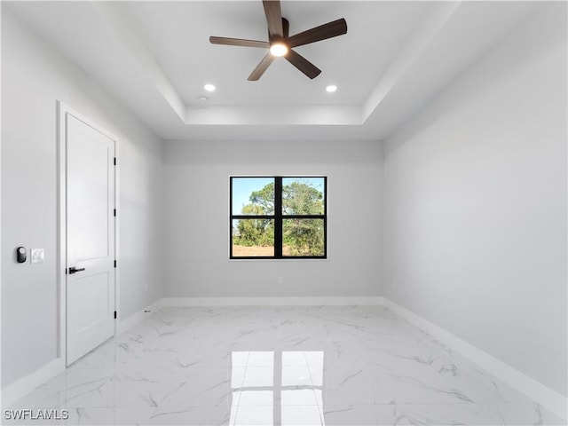 empty room with a raised ceiling and ceiling fan