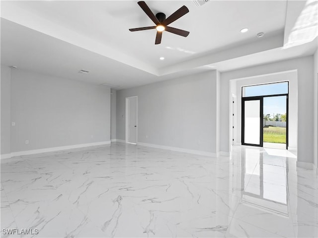 unfurnished room with ceiling fan and a tray ceiling