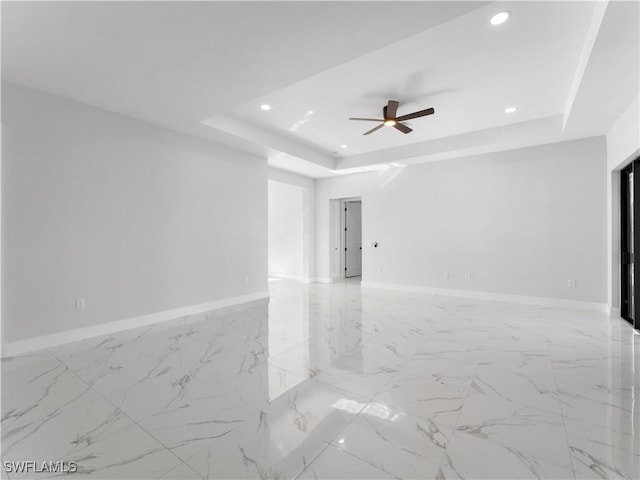 empty room featuring a tray ceiling and ceiling fan