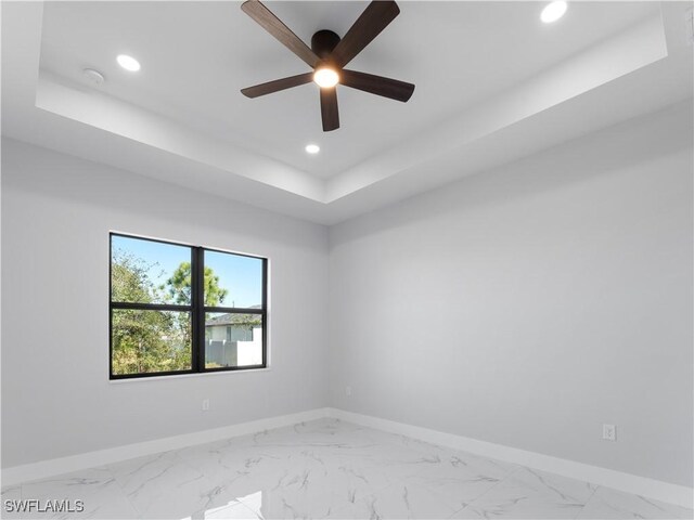 empty room with a tray ceiling and ceiling fan