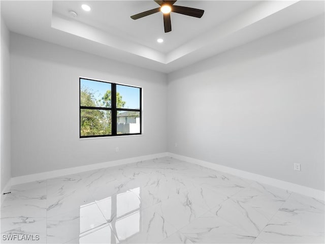 spare room featuring a tray ceiling and ceiling fan