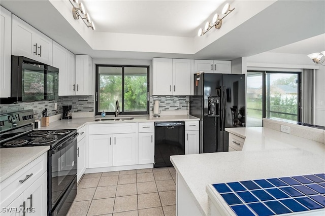 kitchen featuring backsplash, black appliances, white cabinets, a raised ceiling, and sink