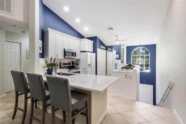 kitchen with sink, a kitchen breakfast bar, lofted ceiling, a kitchen island, and appliances with stainless steel finishes