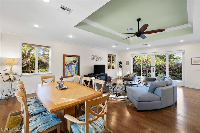 dining space with a tray ceiling, dark wood-style flooring, and visible vents