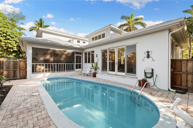 back of property featuring a patio, a fenced in pool, and a sunroom