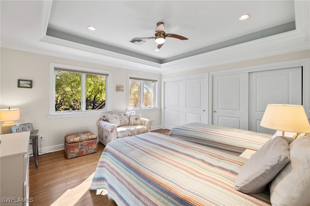 bedroom featuring a tray ceiling, ceiling fan, light hardwood / wood-style flooring, and ornamental molding